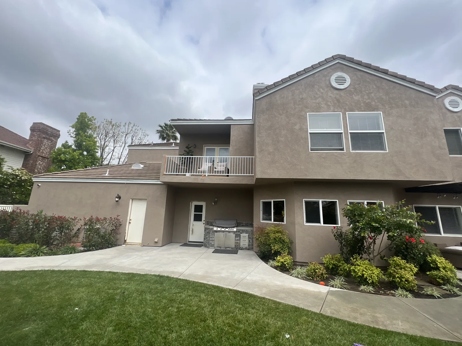 Large two-story stucco home in Alhambra with tile roof and balcony after repainting