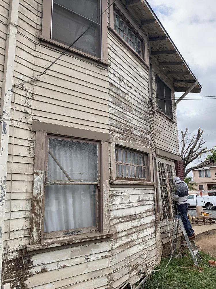 Two-story Alhambra home with paint failed back to bare wood across the lap siding and window trim