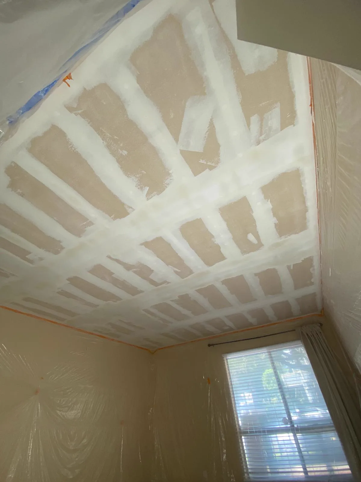 Vaulted ceiling fully taped and coated with the walls masked in plastic sheeting