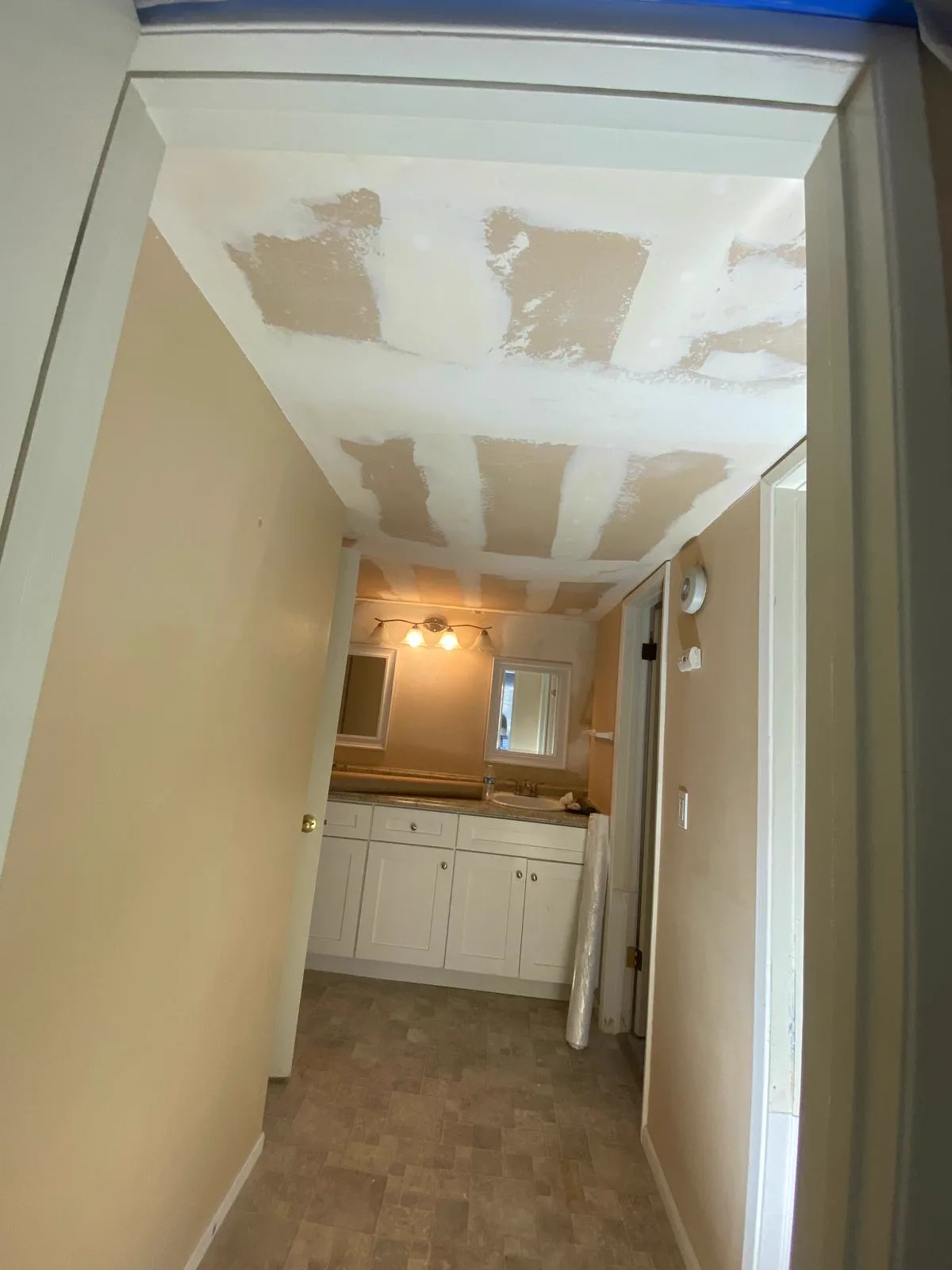 Hallway ceiling with drywall patches taped and coated before texture matching