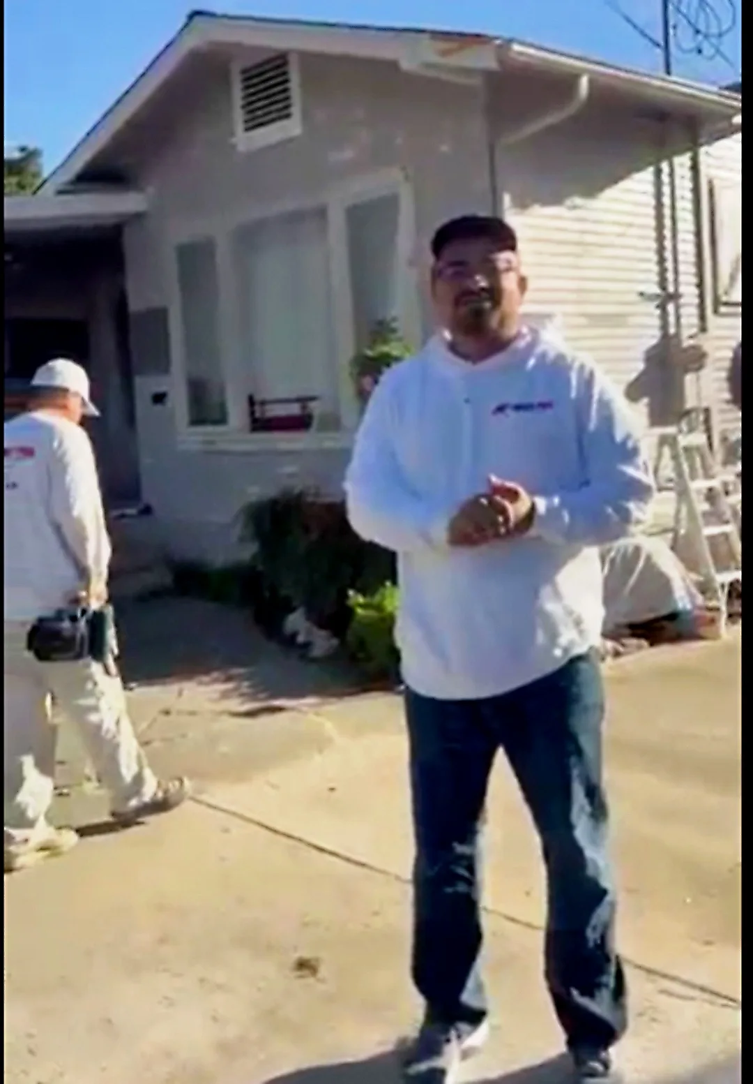 Ivan Martinez of Ivan's Pro Painting on a job site, crew working on the house behind him