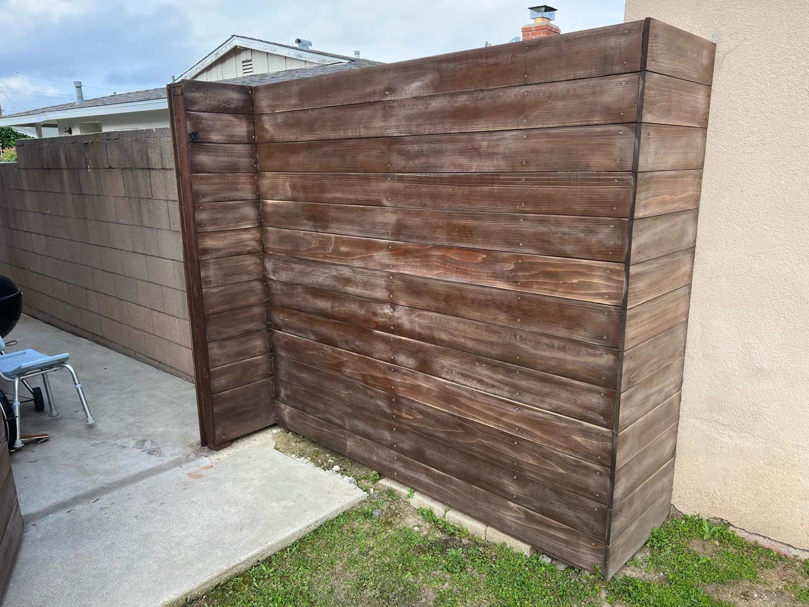 Weathered horizontal wood fence with faded uneven stain before refinishing