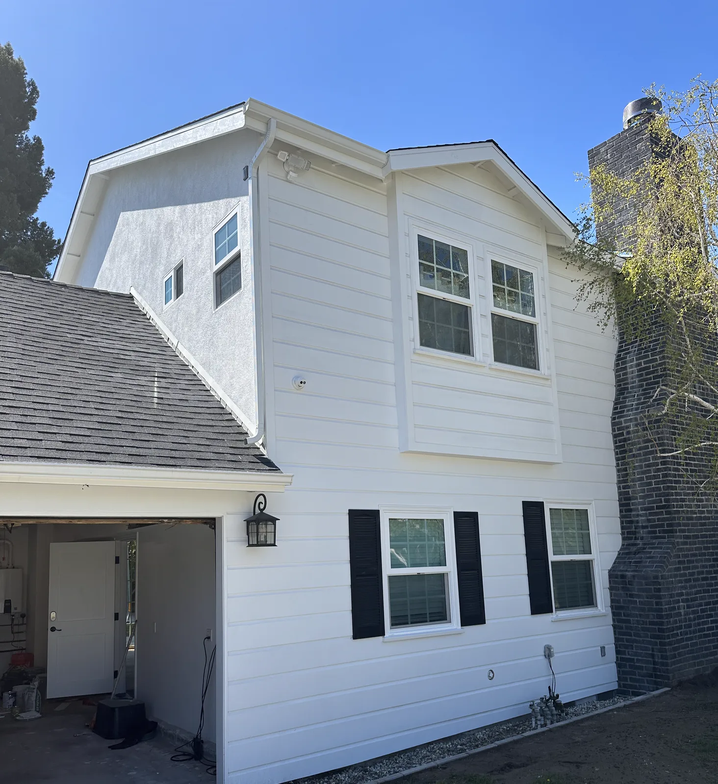 White lap siding and stucco on a two-story Pasadena home with black shutters after exterior painting