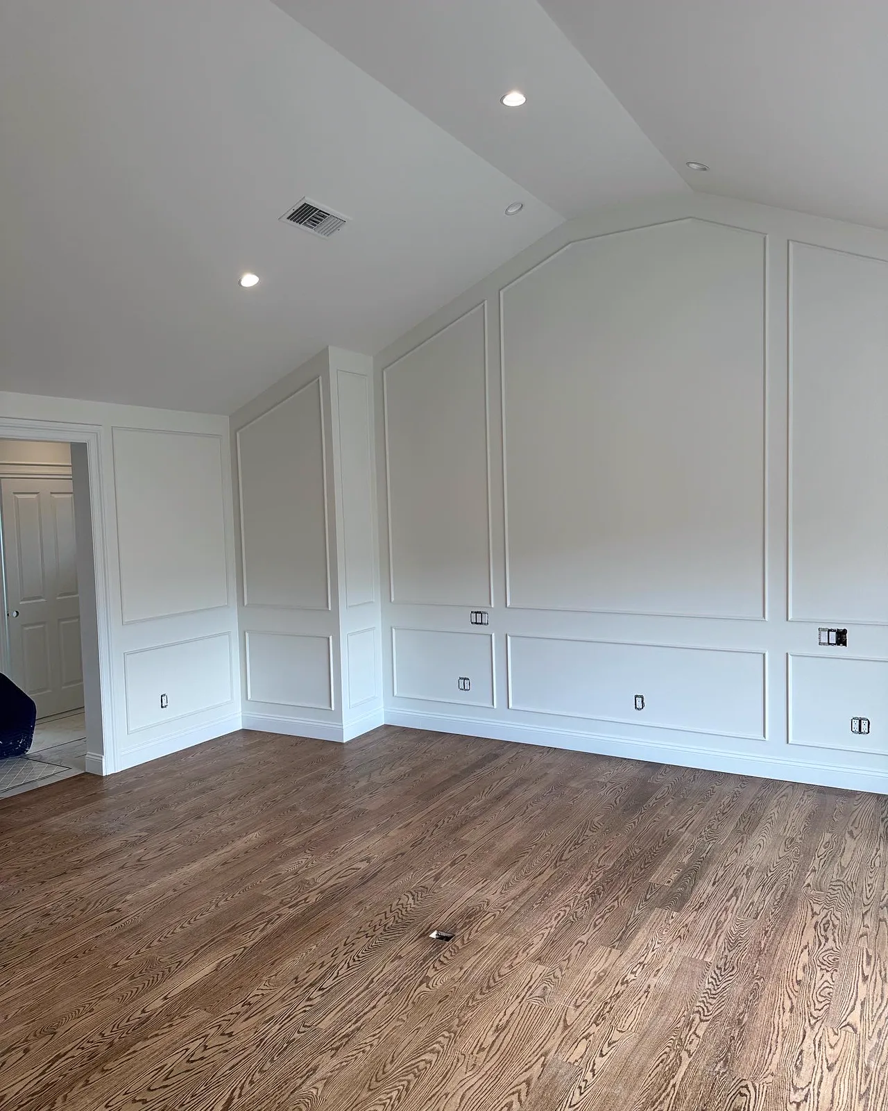 Vaulted Pasadena room finished with white panel moulding walls and oak floors