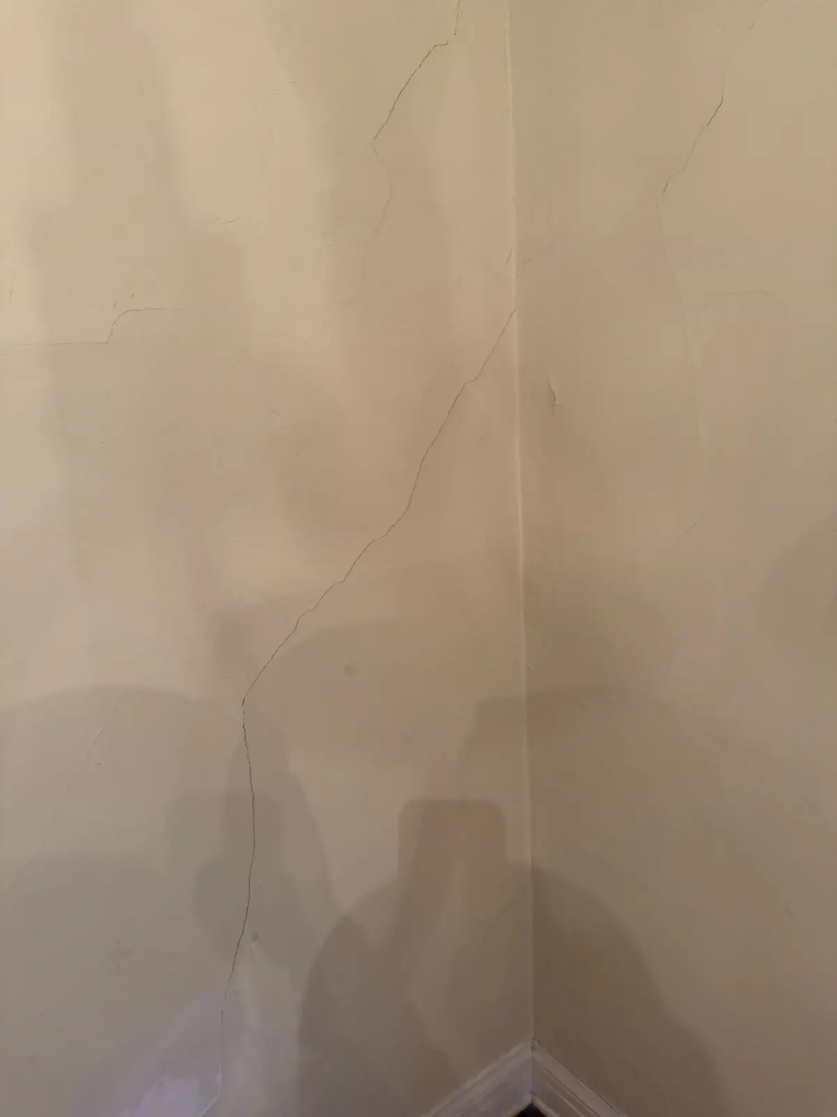Close-up of hairline cracks running across an old plaster wall in a Pasadena home