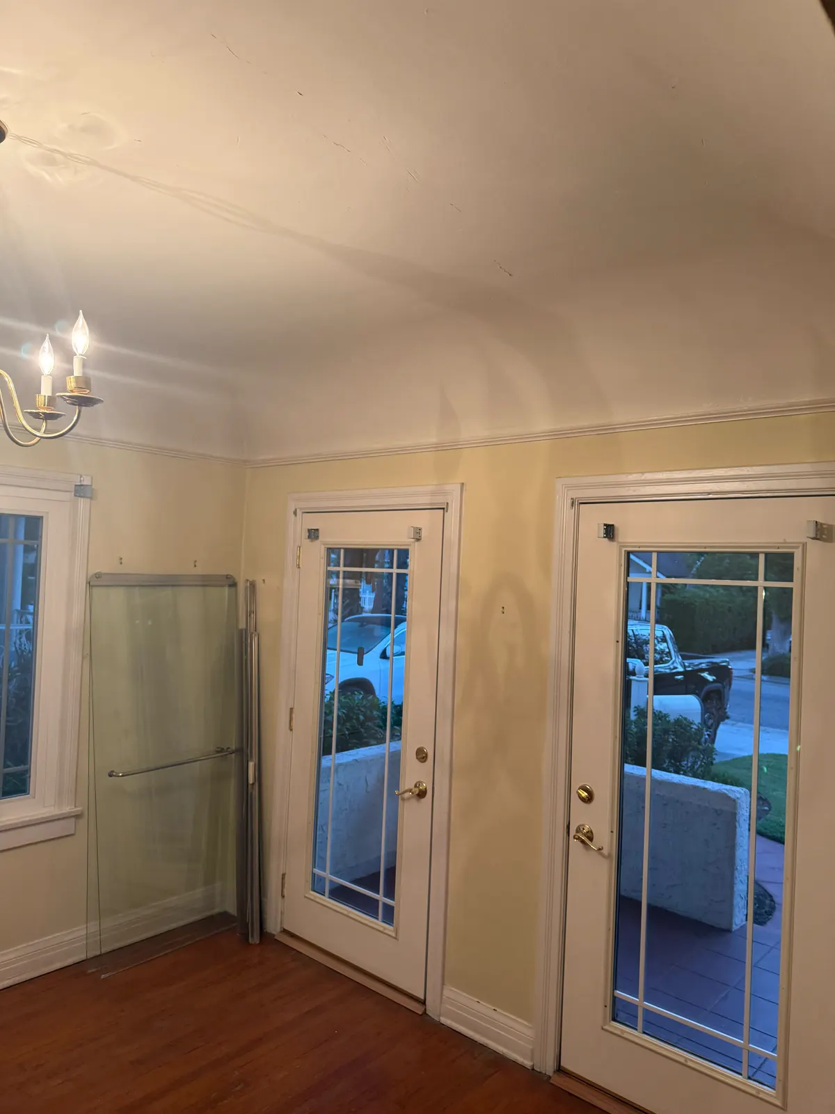 Pasadena dining room with a chandelier and French doors, plaster walls before repair