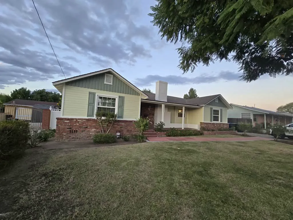The same Pasadena ranch from the other front corner, sage gable and shutters above the brick planter