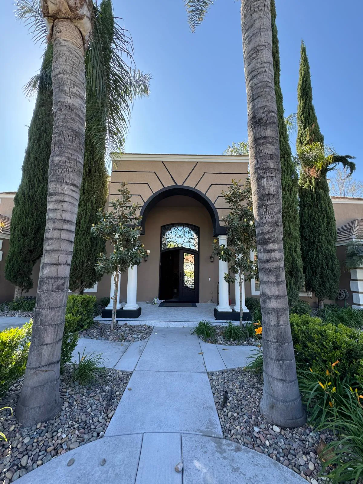 Finished arched entry of a South Pasadena home with palms and cypress after exterior repainting