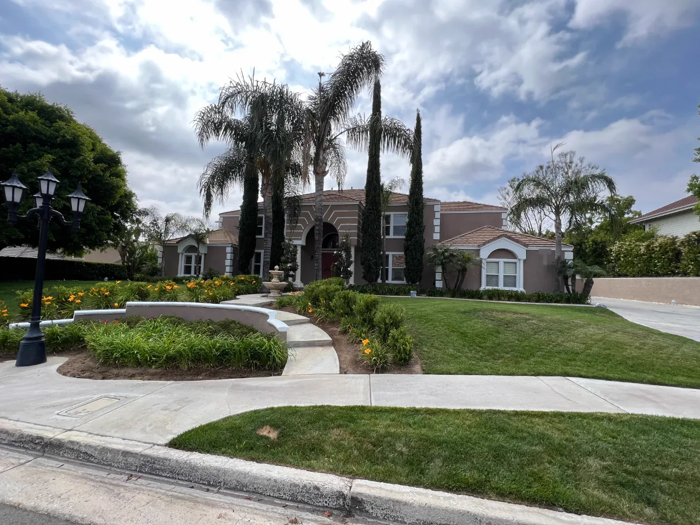Two-story South Pasadena home with palms and a curved front walk after exterior repainting